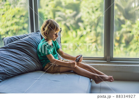 Little blond boy playing games on smartphone Little blond boy playing games on smartphone 88334927