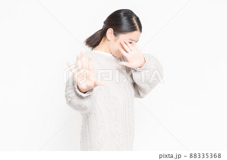 白い背景の前に立ってNGのジェスチャーをする女性 白い背景の前に立ってNGのジェスチャーをする女性 88335368
