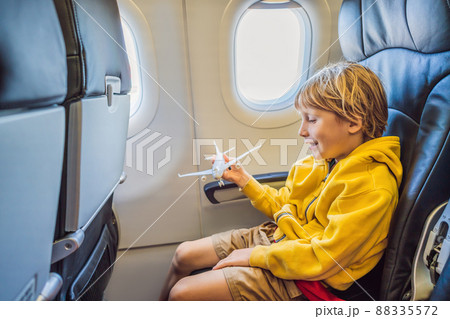 Little boy play with toy plane in the commercial jet airplane flying on vacation Little boy play with toy plane in the commercial jet airplane flying on vacation 88335572
