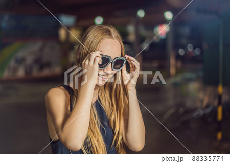 Young woman tourist trying on glasses on Walking street Asian market Young woman tourist trying on glasses on Walking street Asian market 88335774