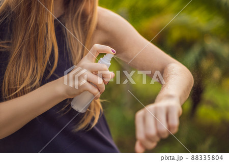 Woman spraying insect repellent on skin outdoor Woman spraying insect repellent on skin outdoor 88335804