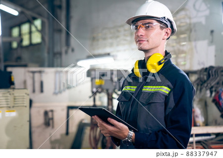 Young factory worker using adept tablet computer in a workshop building 88337947