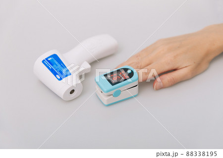 Pulse oximeter and thermometer gun on white background. Infrared isometric thermometer gun to check body temperature for virus symptoms. Measuring oxygen saturation, pulse rate and oxygen levels. 88338195