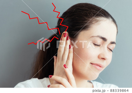 Portrait of a suffering young Caucasian woman covering her ear with her hands from pain or a loud sound. Gray background. The concept of deafness and ear diseases 88339864
