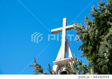 Christian church cross with bells on blue sky. Symbol of religion. Catholic church in Poland and bell tower with cross. Religion and Christianity Christian church cross with bells on blue sky. Symbol of religion. Catholic church in Poland and bell tower with cross. Religion and Christianity 88340099