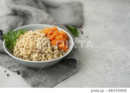 boiled pearl barley with butter and carrots in a gray plate 88340906