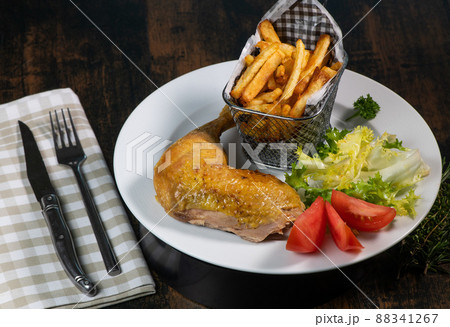 Roasted dinner on white plate containing chicken and potato, homemade fries 88341267