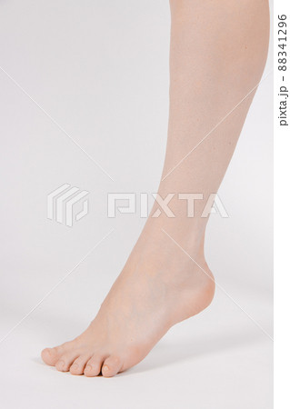 Barefoot and legs isolated on white background. Closeup shot of healthy beautiful female feet. Health and beauty concept. Side view of human foot ream with neutral manicure or pedicure. Sole of foot. 88341296