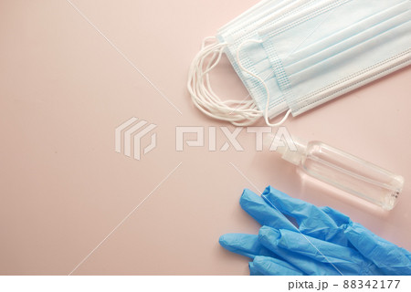 Surgical masks, thermometer and hand sanitizer on color background  88342177
