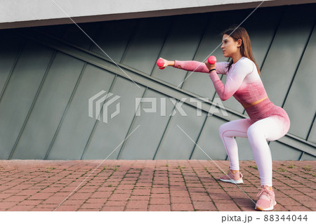 Girl doing squats workout with dumbbells	 88344044