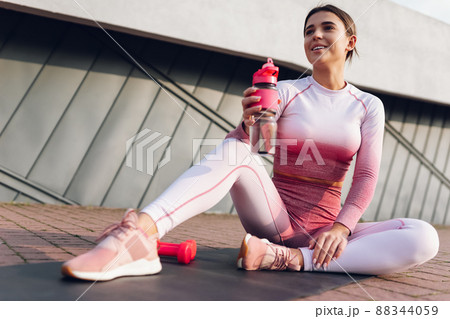 Fitness girl sitting with a bottle of water on the mat 88344059