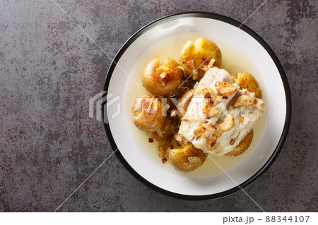 Cod fillet baked in olive oil with garlic served with potatoes close-up in a plate. horizontal top view Cod fillet baked in olive oil with garlic served with potatoes close-up in a plate. horizontal top view 88344107