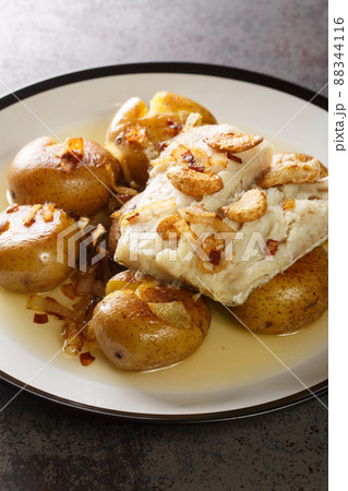 Traditional Portuguese Bacalhau a Lagareiro Oven Cooked Codfish with Potatoes closeup in the plate. Vertical Traditional Portuguese Bacalhau a Lagareiro Oven Cooked Codfish with Potatoes closeup in the plate. Vertical 88344116