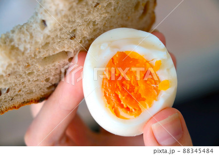 The girl holds a boiled egg and bread in her hand, a quick and healthy snack. The girl holds a boiled egg and bread in her hand, a quick and healthy snack. 88345484
