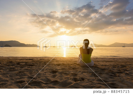 Single young woman sitting alone and looking through the sea on the beach. Single young woman sitting alone and looking through the sea on the beach. 88345715