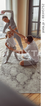 Jolly sporty family doing gymnastics together indoors 88345752