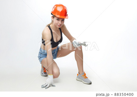 attractive blonde in an orange protective helmet and a wrench in her hands. attractive blonde in an orange protective helmet and a wrench in her hands. 88350400