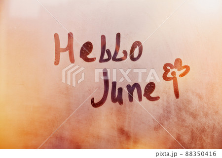 Handwritten text Hello June and flower shape on wet orange window 88350416