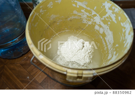 White putty in a bucket of water. Preparation of mortar for finishing walls and ceilings in the apartment. Repair in the house. DIY. Selective focus White putty in a bucket of water. Preparation of mortar for finishing walls and ceilings in the apartment. Repair in the house. DIY. Selective focus 88350962