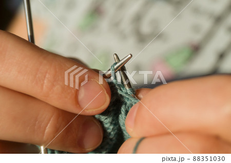 Close-up hand knitting. Hobbies, handicrafts. Knitting warm clothes from woolen fine yarn by hand on metal needles. Selective focus Close-up hand knitting. Hobbies, handicrafts. Knitting warm clothes from woolen fine yarn by hand on metal needles. Selective focus 88351030