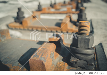 Fastening elements of railway rails to concrete sleepers. Seat rails on sleepers. Large rust bolt with nut. Selective focus Fastening elements of railway rails to concrete sleepers. Seat rails on sleepers. Large rust bolt with nut. Selective focus 88351075