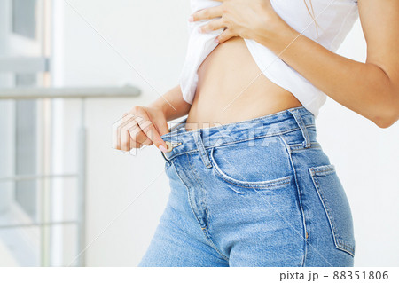 Young slim woman in old big jeans showing her diet results Young slim woman in old big jeans showing her diet results 88351806