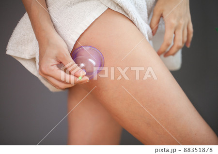 A woman does a hip massage with a vacuum jar for an anti-cellulite massage. 88351878