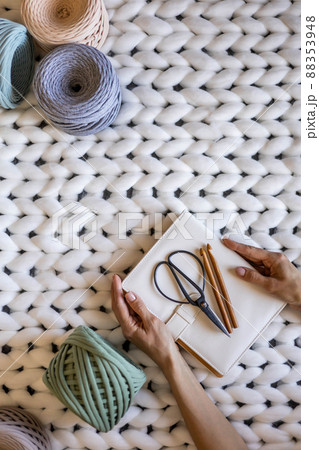 Closeup creative female hands holding elegant notepad surrounded by multicolored ribbon yarn 88353948