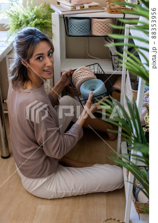 Happy blonde woman posing with ribbon yarn clews during seasonal cupboard tidying up home workplace 88353956