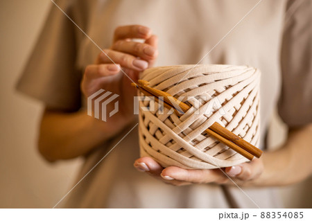 Closeup beautiful female hands hold hank reel of beige ribbon yarn and wooden crochet needles Closeup beautiful female hands hold hank reel of beige ribbon yarn and wooden crochet needles 88354085