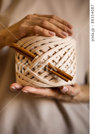 Closeup beautiful female hands hold hank reel of beige ribbon yarn and wooden crochet needles 88354087