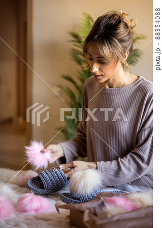 Portrait happy blonde woman art clothes designer creative ribbon yarn knitted slippers with pom pom Portrait happy blonde woman art clothes designer creative ribbon yarn knitted slippers with pom pom 88354088