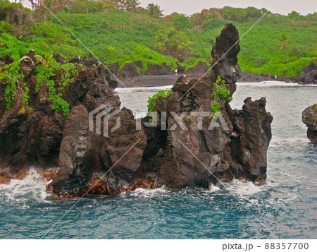 Visitors Explore the Lava Cliffs at Waianapanapa State Park in Hana, Hawaii on the island of Maui 88357700