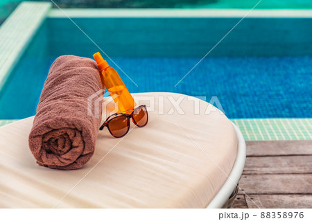 Suntan vacation hotel swimming pool background with travel accessories to tan on sun loungers holidays in Caribbean destination. Tanning oil, towel and sunglasses women objects Suntan vacation hotel swimming pool background with travel accessories to tan on sun loungers holidays in Caribbean destination. Tanning oil, towel and sunglasses women objects 88358976