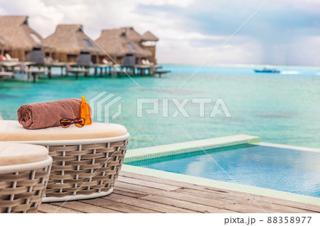 Luxury Bora Bora overwater bungalow villas high end hotel in Tahiti, French Polyneisa. Ocean view summer travel destination resort background, sun lounger with towel , sunscreen and sunglasses 88358977