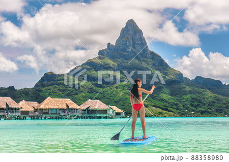Tahiti Bora Bora island vacation recreational activity watersport woman paddleboarding on SUP Stand Up Paddle Board at luxury resort hotel in French Polynesia. Mt Otemanu summer holiday landscape Tahiti Bora Bora island vacation recreational activity watersport woman paddleboarding on SUP Stand Up Paddle Board at luxury resort hotel in French Polynesia. Mt Otemanu summer holiday landscape 88358980