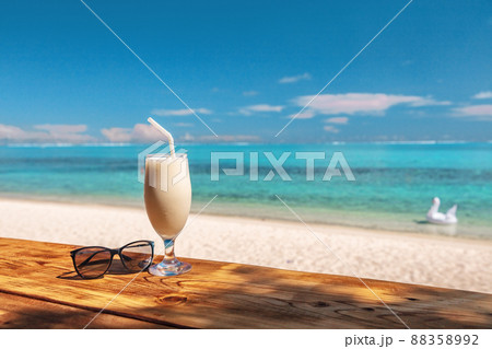 Coconut shake pina colada drink cocktail milkshake at beach bar in Bora Bora island, Tahiti, French Polynesia. Ocean view with tall milk drinking glass on table Coconut shake pina colada drink cocktail milkshake at beach bar in Bora Bora island, Tahiti, French Polynesia. Ocean view with tall milk drinking glass on table 88358992