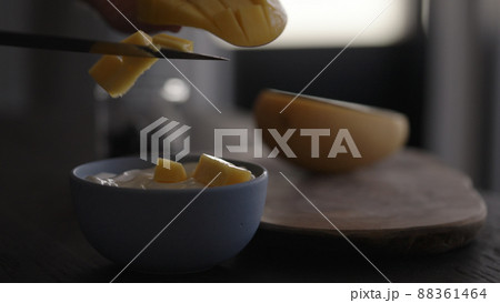 add fresh mango to yogurt in bowl 88361464