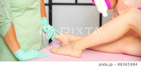 Procedure sugaring. A cosmetologist is sprinkling talcum powder on a young female leg before the depilation procedure 88365984