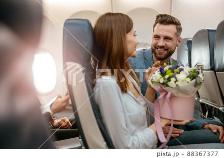 Joyful man and woman with flowers traveling by airplane 88367377