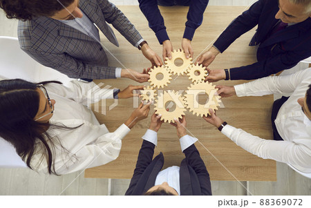People stacking wooden gears next to each other, symbolizing development and success. 88369072