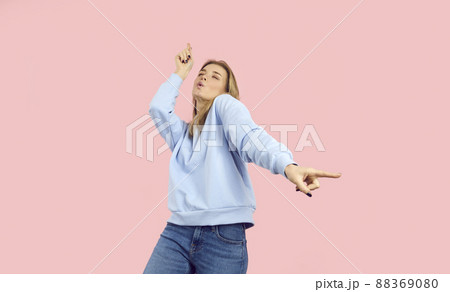 Happy beautiful young woman enjoying music and dancing isolated on pink background 88369080