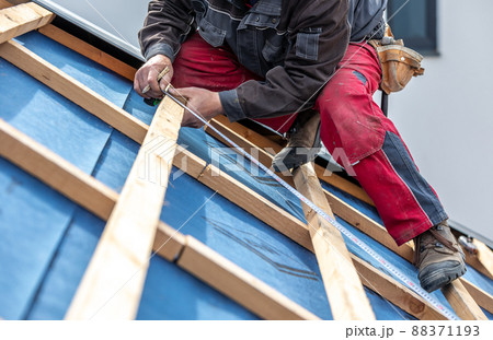 Craftsman or construction worker install a new roof, roofing tools, new metallic roof or metal sheet, building concept Craftsman or construction worker install a new roof, roofing tools, new metallic roof or metal sheet, building concept 88371193