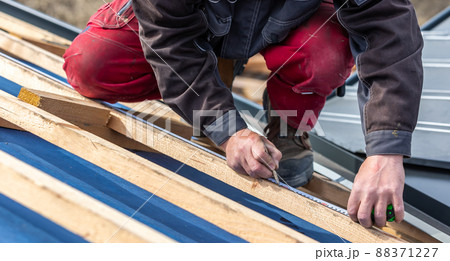 Craftsman or construction worker install a new roof, roofing tools, new metallic roof or metal sheet, building concept Craftsman or construction worker install a new roof, roofing tools, new metallic roof or metal sheet, building concept 88371227