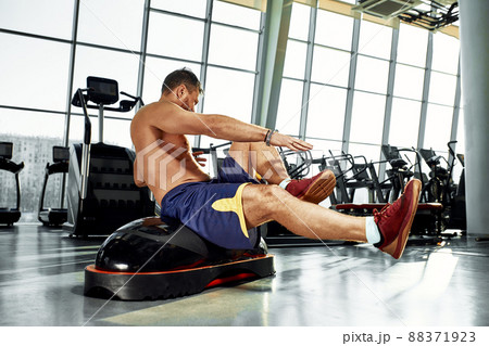 Handsome muscular men works out on functional training soft platform on a background of gym. Handsome muscular men works out on functional training soft platform on a background of gym. 88371923