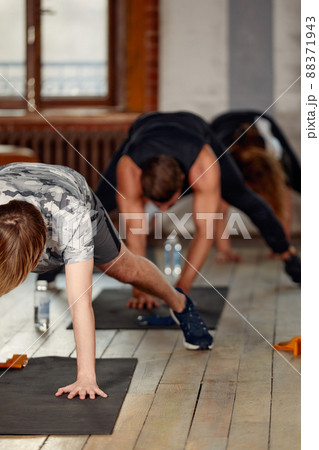 group of athletic young people in sportswear doing push ups or plank at the gym, group fitness concept 88371943