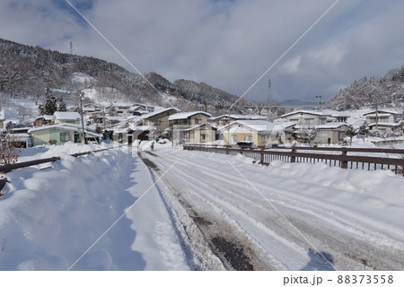 正月寒波の晴れ間に雪の反射が眩しい長野県中野市豊津地区で、雪かきを終えたおばあちゃんが帰路に着く 88373558
