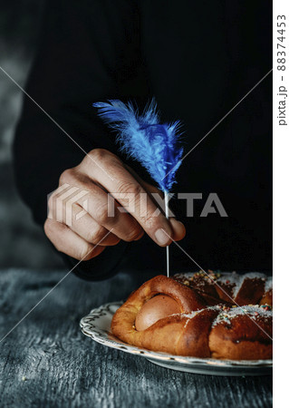 man decorates a Spanish mona de pascua cake 88374453
