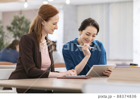 タブレットを見ながら話す外国人と日本人の女性　 88374836