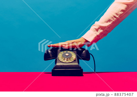 Retro objects, gadgets. Female hand holding handset of vintage phone isolated on blue and pink background. Vintage, retro fashion style. Pop art photography. Retro objects, gadgets. Female hand holding handset of vintage phone isolated on blue and pink background. Vintage, retro fashion style. Pop art photography. 88375407